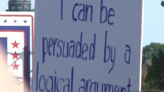 A sign reads "I can be persuaded by a logical argument"