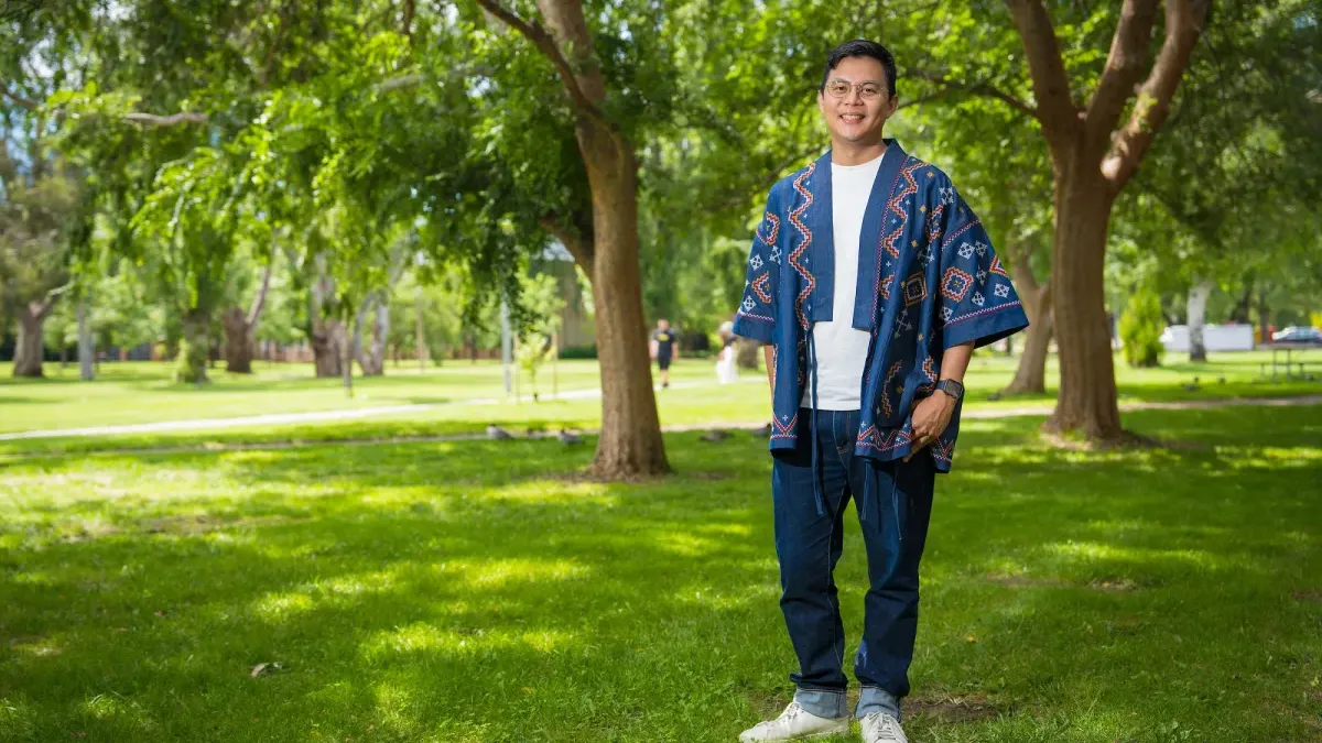 A man standing with trees in the background. 