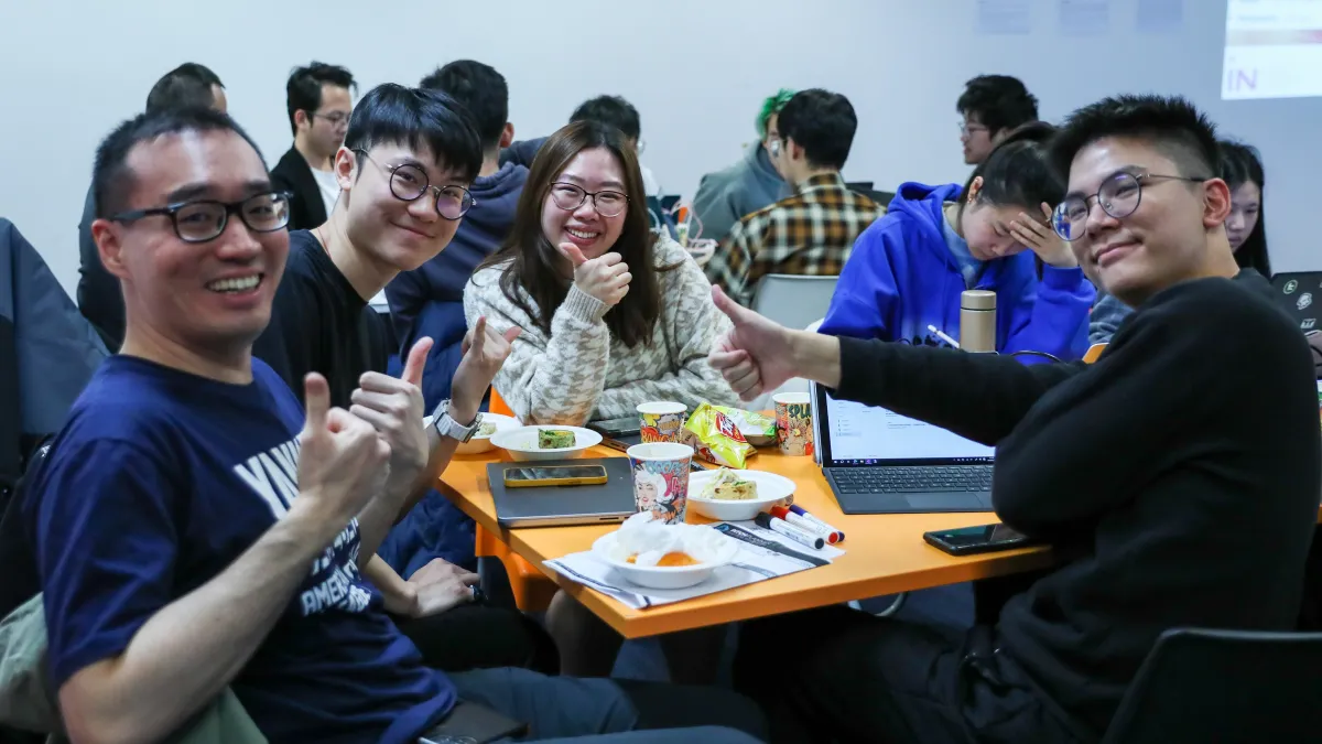 A group of students smiling with their thumbs up. 