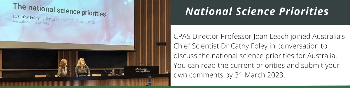 Two women sitting on a stage with a projector sharing slide of title of their topic, "National science priorities."