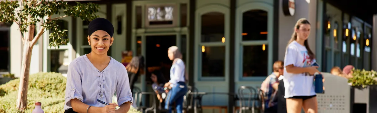 A girl holding a book smiling at the camera