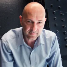 Headshot of man with a black backdrop.