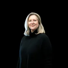 Headshot of Professor Joan Leach in a black sweater and a black backdrop.