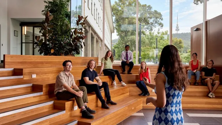 A woman student presenting to a group of other students.