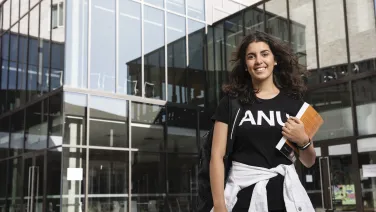 An ANU student holding a book