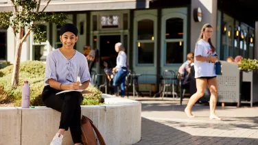 A girl holding a book smiling at the camera