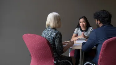 Three people sitting at a table having a discussion