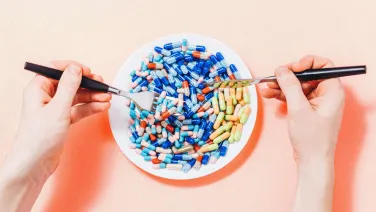 Person cutting into a plateful of pills.